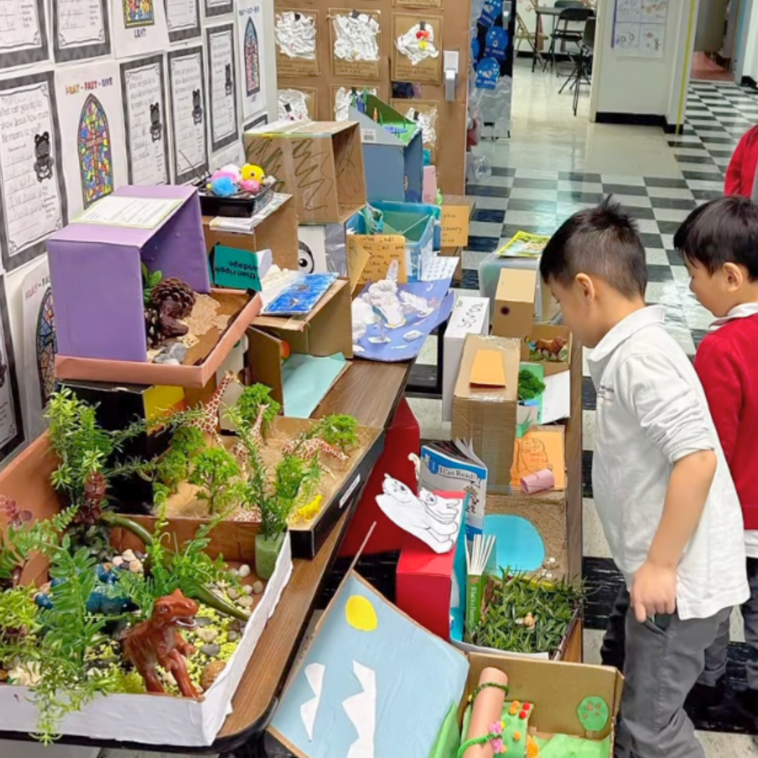 Students of Transfiguration School NYC observe several completed habitat crafts.