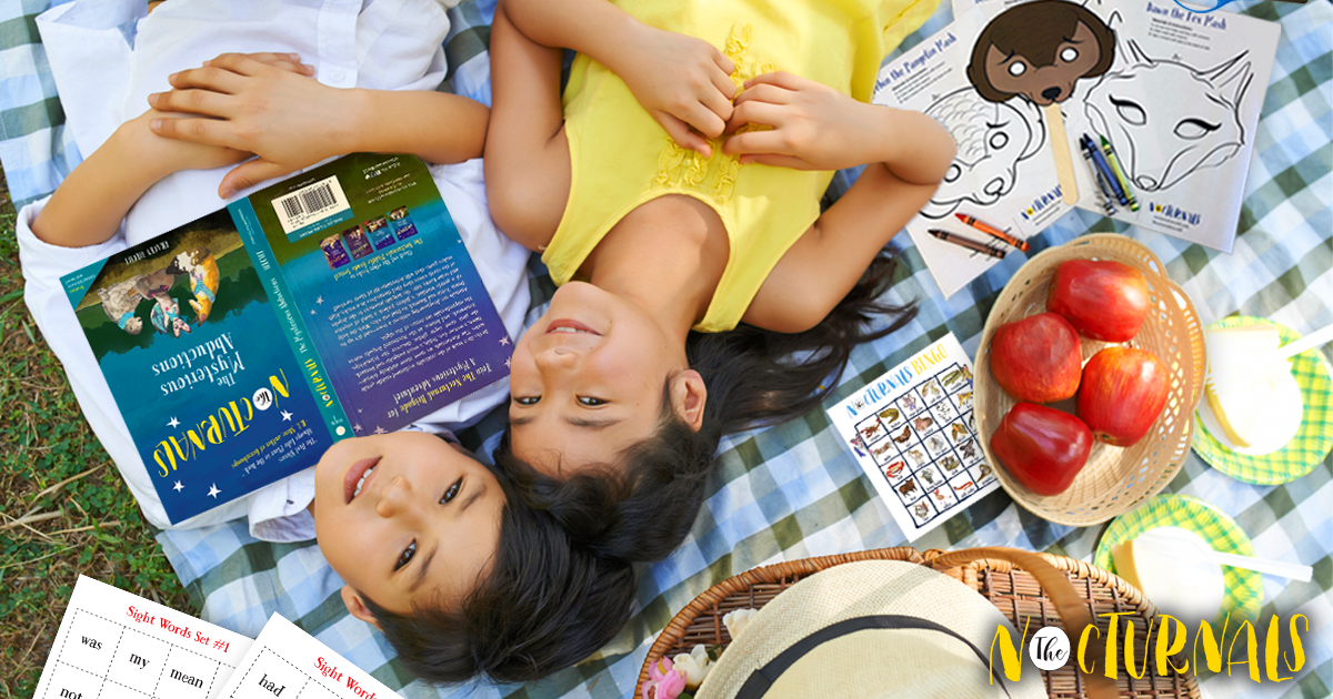 A boy and a girl are laying on top of a blue picnic blanket, looking up with smiles on their faces. On the chest of the boy is The Nocturnals: Mysterious Abductions and surrounded by them are printable activities associated with the book series. 