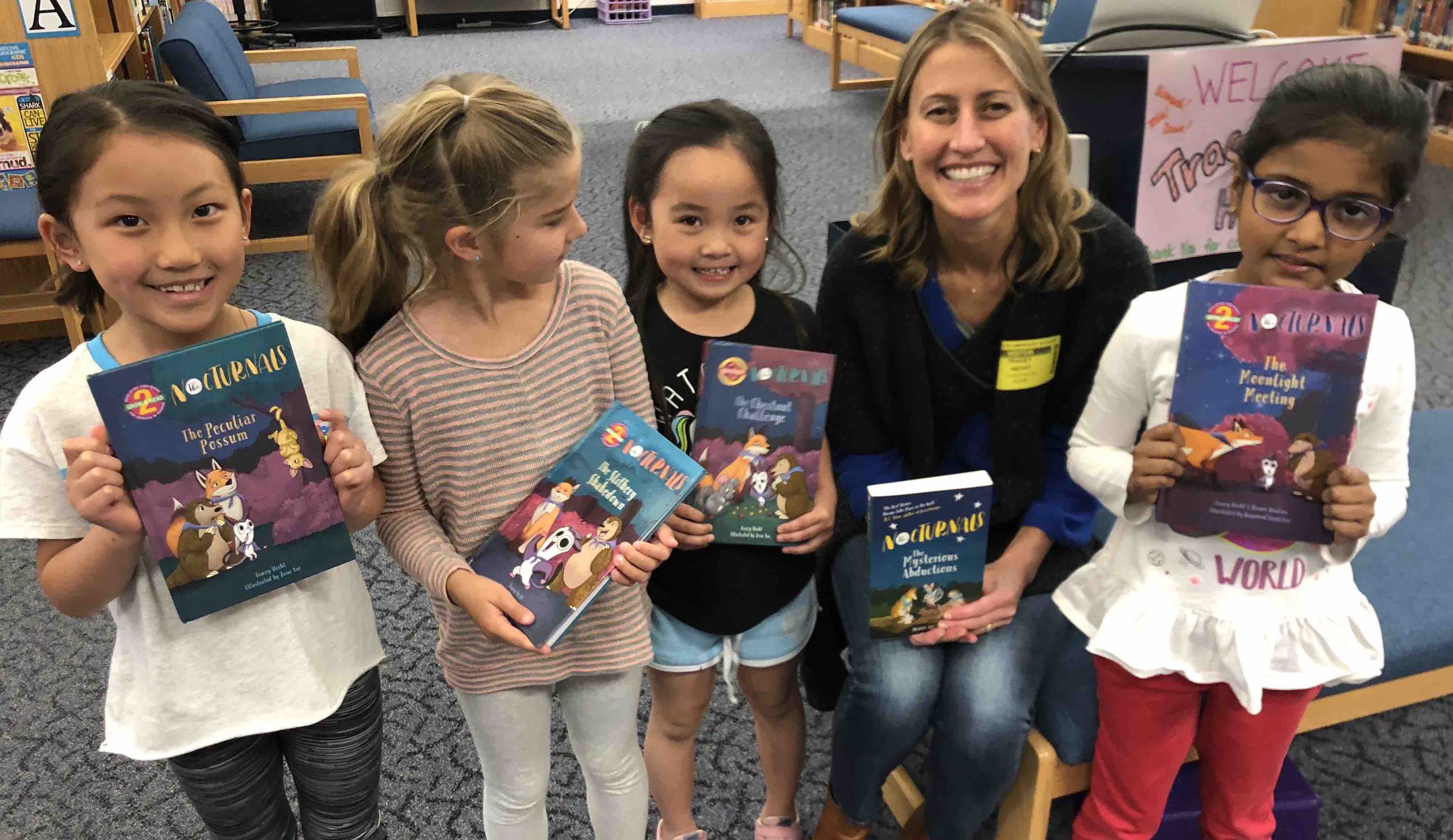 Tracey Hecht, the author of the Nocturnals series, is holding up The Nocturnals Mysterious Abductions while posing with four girls who are all holding up different Early Reader books. 