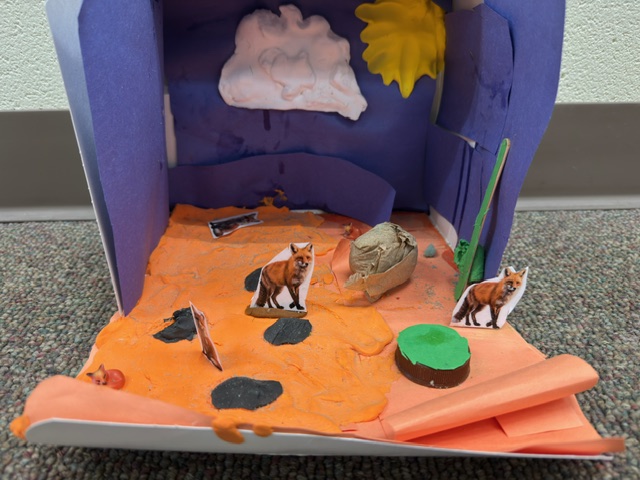 A completed example of the Nocturnals Habitat Activity: a fox diorama made out of paper, cardboard, and other craft supplies.